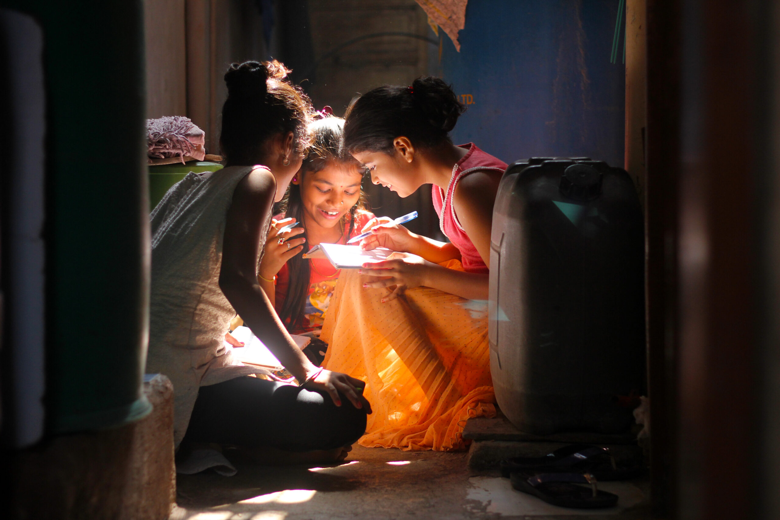 Indian girls sitting together on the floor writing